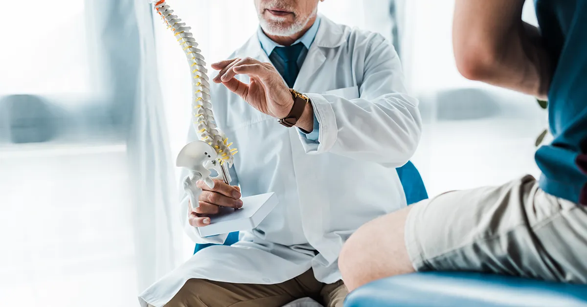 Doctor holding a spine model to explain endoscopic spine surgery to a patient.