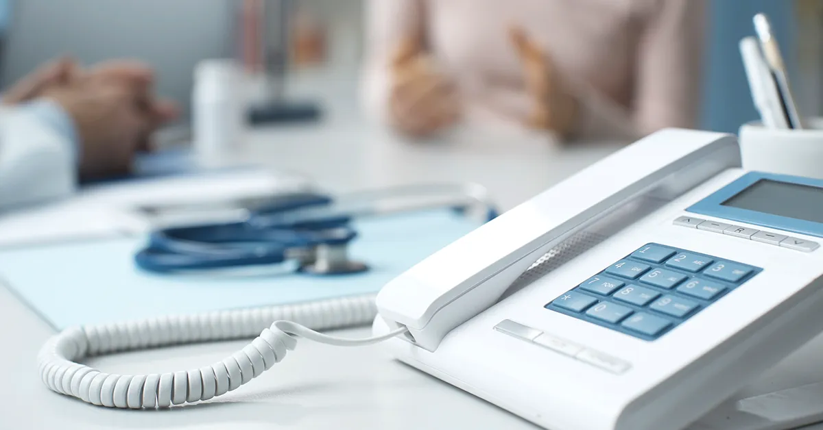 Close-up of a clinic phone and clipboard, symbolizing preparation and consultation for spine surgery.